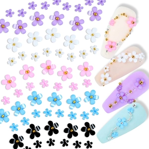 Flat lay of colorful 3D resin nail flowers with center beads for DIY manicure design