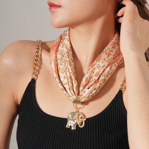 Detail einer rosa Blumenstoffkette mit einem goldfarbenen Elefantenanhänger und Perlen