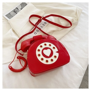 Detail of red vintage telephone shaped shoulder bag with dial and handset accent