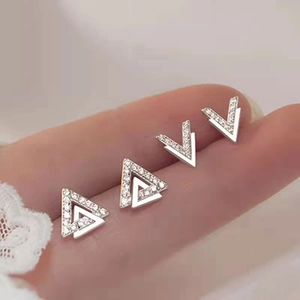 Detailed macro view of geometric silver earrings with pavé crystals on finger