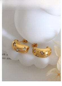 Macro shot of 18K gold plated C-shaped earrings with star engraving and cubic zirconia