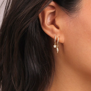 Close-up of gold earring set with cubic zirconia star and lightning bolt charms