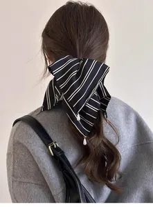 Détail d'un chouchou en satin rayé avec pendentifs perles sur cheveux bruns ondulés