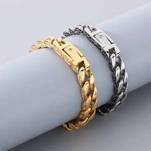 Detail of gold and silver cuban chain bracelets with engraved clasps on a display stand
