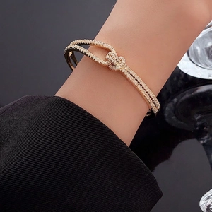 Double-layered gold cuff bracelet with sparkling zircon knot detail for women