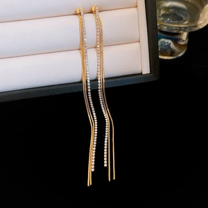 Close-up of golden tassel earrings with sparkling rhinestones on a jewelry box
