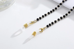 Detail of eyewear chain with black faceted beads, gold metal clips and silicone loops