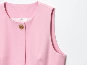 Dettaglio del gilet rosa senza maniche con bottoni dorati e trama del tessuto operato