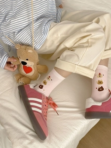 Gros plan de chaussettes en coton rose avec broderie ours mignon et poignets côtelés