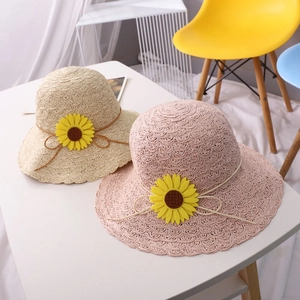 Detail of hand-woven straw hats for kids with sunflower accents in cream and pink