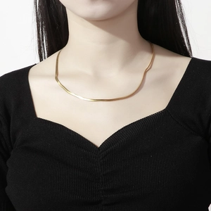 Close-up of a flat gold snake chain necklace elegantly worn on a model's neck