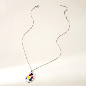Detail of artistic silver palette necklace with colorful paint spots on white surface