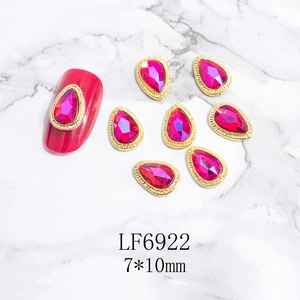 Detalle de gema para uñas de gota rojo rosa con borde de metal dorado y mármol