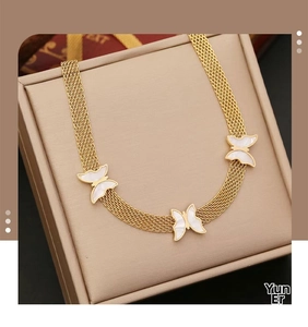 Detail of gold mesh chain necklace featuring three white butterfly pendants in a gift box