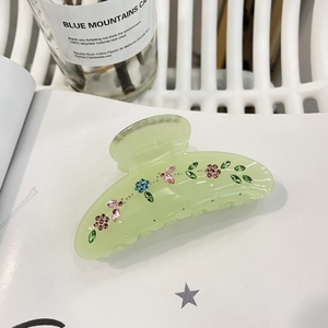 Molla per capelli in acrilico con fiori e brillantini su sfondo di un libro aperto