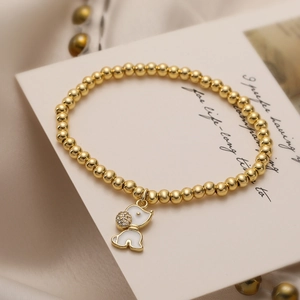 Golden bead stretch bracelet featuring a cute white enamel dog pendant with zircon accents