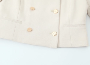 Dettaglio del blazer doppiopetto beige con bottoni in metallo dorato testurizzato