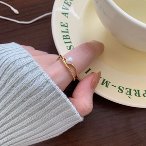 Close-up of minimalist gold twisted band pearl ring on hand with elegant aesthetic