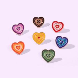 Detail of seven colorful heart enamel pins with gold borders and layered concentric designs