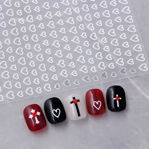 Detail of white hollow heart nail stickers applied on red and black manicured nails