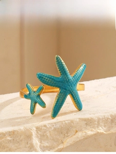 Macro detail of 18K gold-plated starfish ring with turquoise enamel on white stone