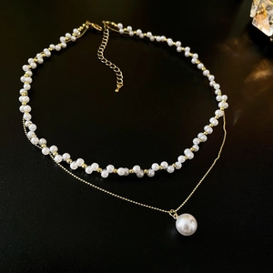Détail d'un collier double rang en perles avec chaîne dorée et fermoir mousqueton