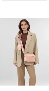 Detail of pink quilted crossbody camera bag with adjustable strap and small coin pouch