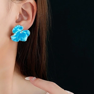 Orecchini a perno a forma di fiore smaltato blu con diamante centrale su una modella