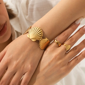 Gold shell stainless steel jewelry set including cuff bracelet and rings on model