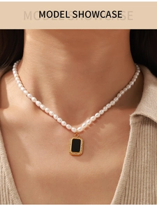 Close-up of pearl necklace with a gold-framed black zircon pendant on a model