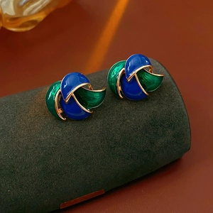 Close-up of vintage blue and green enamel earrings with gold trim on a jewelry stand