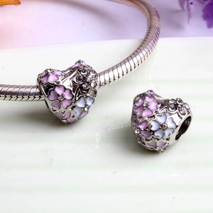 Silver bracelet featuring heart charms with pink and purple enamel flowers and crystals