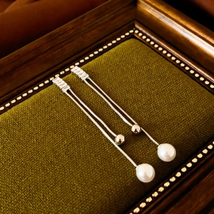 Macro detail of silver tassel earrings with pearls and zircon on green velvet tray