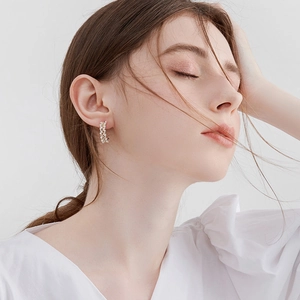 Detail of C-shaped hoop earrings featuring woven pearls and sparkling gold accents
