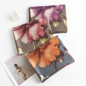 Detail of folded scarves featuring paisley floral patterns and soft decorative fringe edges