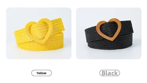Detail of woven straw belts in yellow and black featuring large heart-shaped buckles