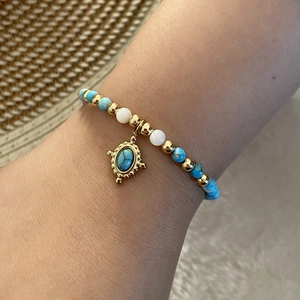 Bohemian beaded bracelet with natural blue stones and vintage gold pendant on wrist