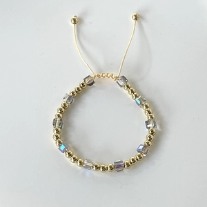 Close-up of colorful crystal cube beads and gold spheres on a braided adjustable bracelet