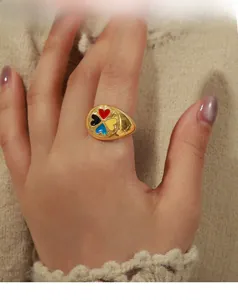 Détail d'une bague chevalière dorée avec trèfle à cœur en émail coloré vintage