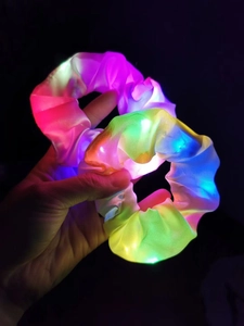 Macro shot of two LED glowing hair scrunchies with vibrant colorful lights in the dark