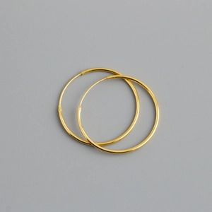 Close-up of polished gold S925 sterling silver hoop earrings on a neutral gray background