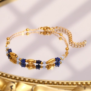 Detail eines 18K vergoldeten Armbands mit blauen Sternperlen und goldenen Anhängern