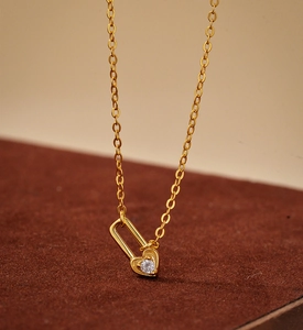 Macro shot of gold heart-lock pendant with clear zircon on a delicate cable chain