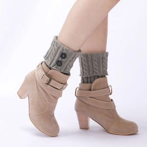 Detail of grey cable knit leg warmers with black buttons paired with beige suede ankle boots