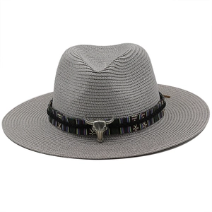 Detail of gray straw fedora hat featuring ethnic band and silver bull skull ornament