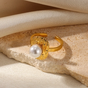 Macro detail of gold hammered texture open ring featuring a white pearl on silk