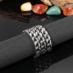 Gros plan d'une bague à maillons argentée sur un support noir avec texture polie