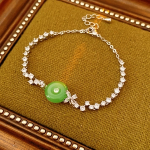 Macro shot of silver zircon chain bracelet with green chalcedony stone on green tray