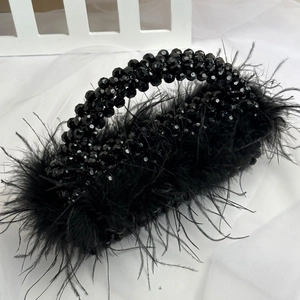 Close-up of black beaded handbag featuring soft ostrich feathers and handcrafted details