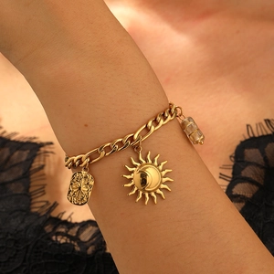 Macro shot of a vintage gold chain bracelet featuring sun, star, and glass pendants